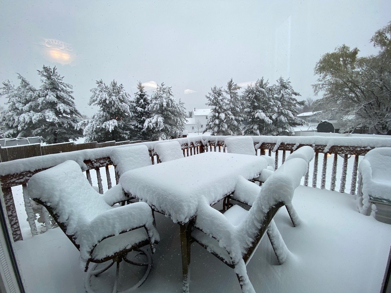 Picture of a backyard patio with a table and chairs covered in about 5 inches of snow, nicely sitting on top of the table